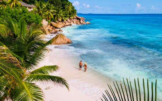 Anse Patates, La Digue Seychelles, a young couple of men and women on a tropical beach during a luxury vacation in Seychelles. Tropical beach Anse Patates, La Digue Seychelles