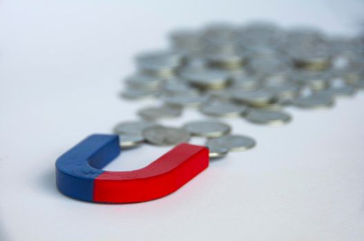 Magnet attracting silver coins with white cover background. Business and law of attraction concept
