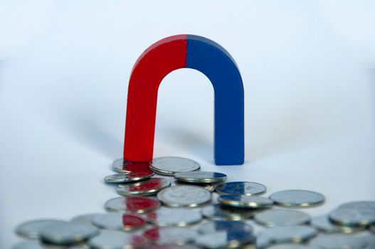 Magnet attracting silver coins with white cover background. Business and law of attraction concept