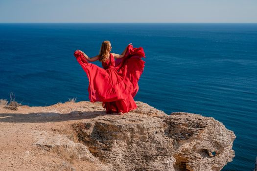 A woman in a red flying dress fluttering in the wind, against the backdrop of the sea