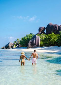 Anse Source d'Argent, La Digue Seychelles, a young couple of Caucasian men and Asian women on a tropical beach during a luxury vacation in Anse Source d'Argent, La Digue Seychelles