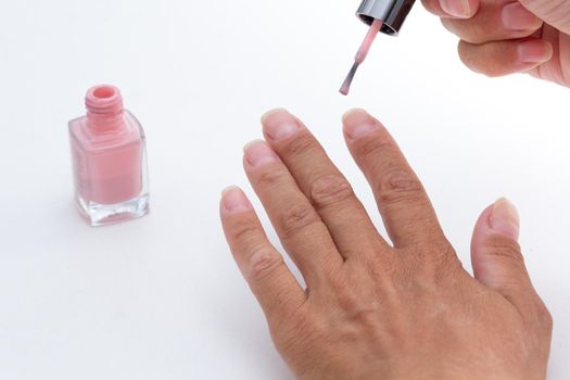 Cropped woman hands painting nails applying pink color nail polish on white background