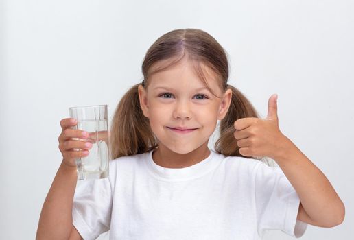 Caucasian beautiful child of 6 years holding glass of pure water looking at camera on white background