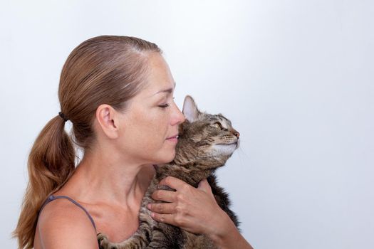 Portrait of caucasian middle aged woman of 40s holding cat on white background looking aside