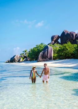 Anse Source d'Argent, La Digue Seychelles, a young couple of Caucasian men and Asian women on a tropical beach during a luxury vacation in Anse Source d'Argent, La Digue Seychelles