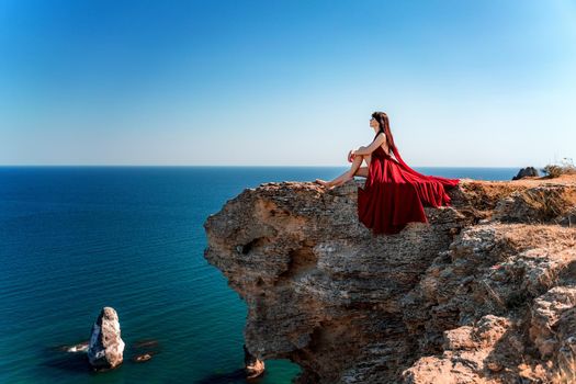 A woman in a red flying dress fluttering in the wind, against the backdrop of the sea