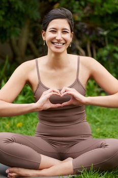 Good health is great nourishment for your body and soul. Portrait of a young woman making a heart shape with her hands while exercising outdoors