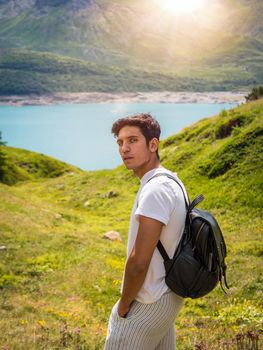 Half body shot of handsome young man outdoor in the mountains, looking at camera