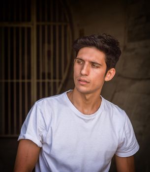 Attractive green eyed young man, looking away to a side, wearing white t-shirt