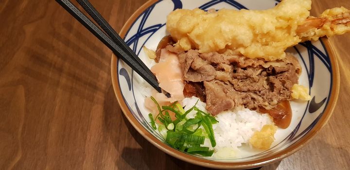 Japanese traditional food beef teriyaki with stickt rice and tempura shrimp sliced spring onion in a bowl