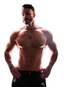 Shirtless muscular male bodybuilder in studio isolated on white, with dramatic back lighting