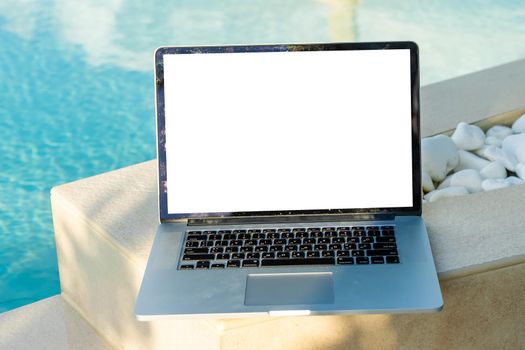 Computer laptop with blank screen near the swimming pool