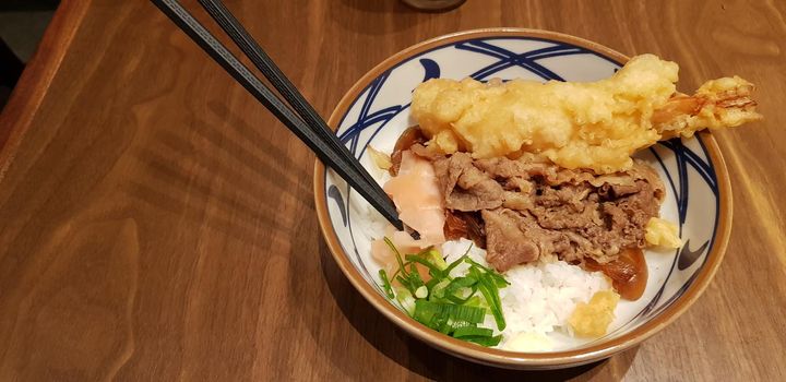 Japanese traditional food beef teriyaki with stickt rice and tempura shrimp sliced spring onion in a bowl