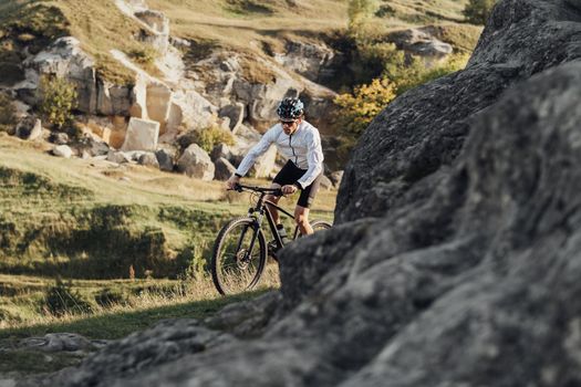 Professional Male Cyclist Riding Mountain Bike on Trail Among Rocky Terrain