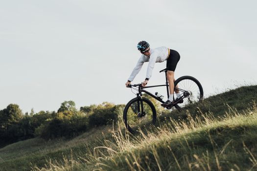 Professional Cyclist Descends a Slope on Mountain Bike, Sportsman Going Down from Hill on Bicycle, Copy Space