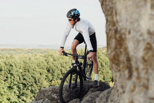Equipped Professional Male Cyclist Riding Mountain Bike on the Trail Among Rocky Terrain, Adult Man Enjoying His Extreme Hobby Standing with Bicycle on the Rock with Panoramic View