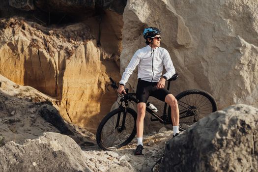 Professional Male Cyclist Leans on Bike and Adult Man Enjoying Rest During His Ride on Bicycle