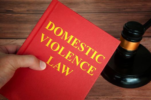 Domestic violence law text on law book with judge gavel on wooden desk background. Law concept
