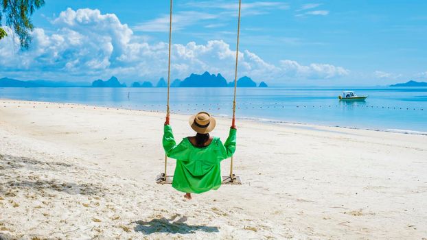 woman on the beach of the tropical Island Naka Island near Phuket Thailand, a woman on a swing on the beach in Thailand