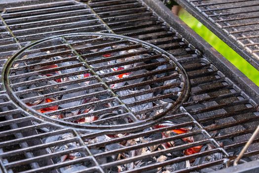 Barbecue device with grill grate. Hot coals for cooking steaks. Selective focus.