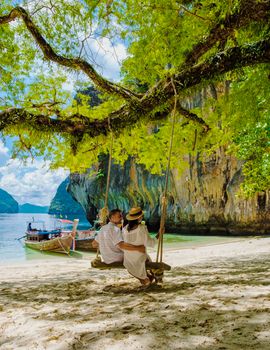 Koh Lao Lading near Koh Hong Krabi Thailand, beautiful beach with longtail boats, a couple of European men, and an Asian woman on the beach.