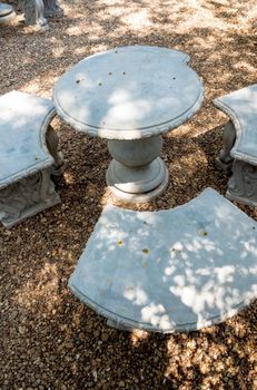 Stucco outdoor table set on the gravel floor in the garden