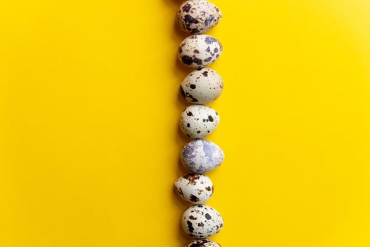Top view - Quail eggs on bright yellow background. Minimal Happy Easter composition.