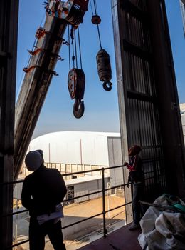 Hoist of crane at the window of industrial plant