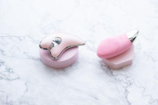 Ultrasonic Skin Scrubber Exfoliating Wand on pink background with bathroom items