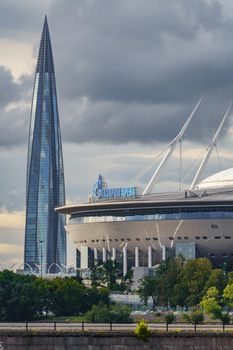 Russia, St. Petersburg, 29 July 2022: The new building of football stadium Gazprom Arena, the sliding metal roof glitters with spires in the sun, the skyscraper Lakhta for the gas company Gazprom. High quality photo