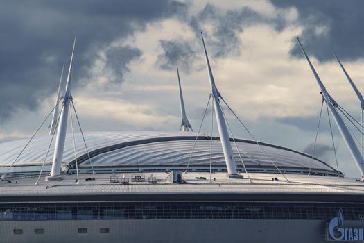 Russia, St. Petersburg, 29 July 2022: The new building of football stadium Gazprom Arena, the sliding metal roof glitters with spires in the sun, the gas company Gazprom. High quality photo