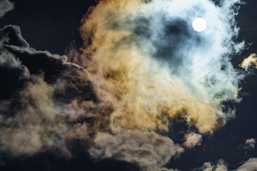Diffraction of light on drops of supercooled water in clouds, rainbow clouds against the blue sky in clear sunny weather, irisation of cumulus clouds, optical phenomenon, spectral colors. High quality photo