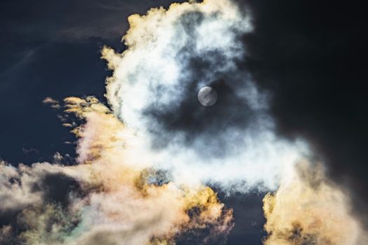 Diffraction of light on drops of supercooled water in clouds, rainbow clouds against the blue sky in clear sunny weather, irisation of cumulus clouds, optical phenomenon, spectral colors. High quality photo