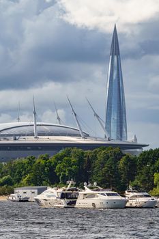 Russia, St. Petersburg, 29 July 2022: The new building of football stadium Gazprom Arena, sailing and motor boats are moored near embankment, the skyscraper Lakhta for the gas company Gazprom. High quality photo