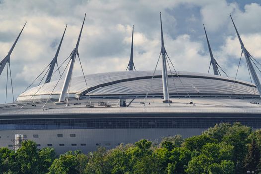 Russia, St. Petersburg, 29 July 2022: The new building of football stadium Gazprom Arena, the sliding metal roof glitters with spires in the sun, the gas company Gazprom. High quality photo