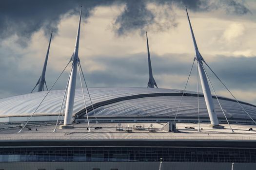 Russia, St. Petersburg, 29 July 2022: The new building of football stadium Gazprom Arena, the sliding metal roof glitters with spires in the sun, the gas company Gazprom. High quality photo