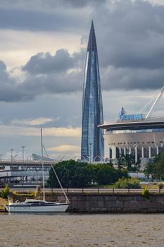 Russia, St. Petersburg, 29 July 2022: The new building of football stadium Gazprom Arena, the sliding metal roof glitters with spires in the sun, the skyscraper Lakhta for the gas company Gazprom. High quality photo
