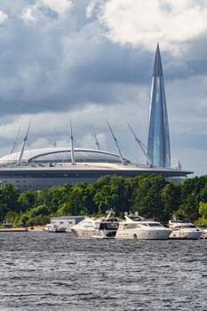 Russia, St. Petersburg, 29 July 2022: The new building of football stadium Gazprom Arena, sailing and motor boats are moored near embankment, the skyscraper Lakhta for the gas company Gazprom. High quality photo