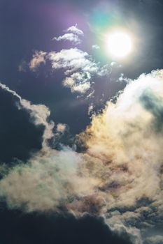 Diffraction of light on drops of supercooled water in clouds, rainbow clouds against the blue sky in clear sunny weather, irisation of cumulus clouds, optical phenomenon, spectral colors. High quality photo