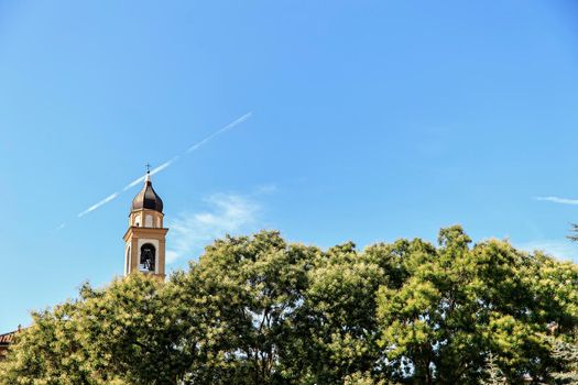 Church bell tower in the trees in Rovigo, Italy