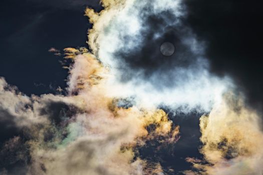 Diffraction of light on drops of supercooled water in clouds, rainbow clouds against the blue sky in clear sunny weather, irisation of cumulus clouds, optical phenomenon, spectral colors. High quality photo