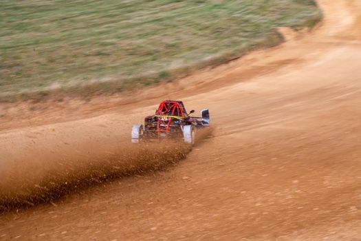 buggies on the autocross track, skidding, dust and dirt flying under the tires.