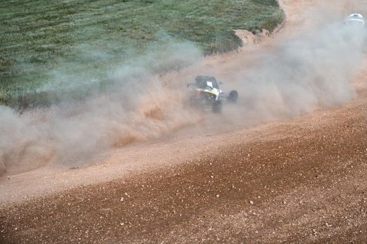 buggies on the autocross track, skidding, dust and dirt flying under the tires.
