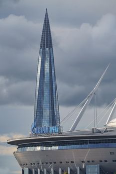 Russia, St. Petersburg, 29 July 2022: The new building of football stadium Gazprom Arena, the sliding metal roof glitters with spires in the sun, the skyscraper Lakhta for the gas company Gazprom. High quality photo