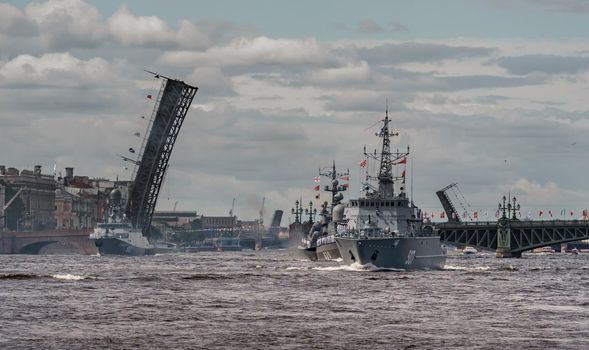 Russia, St. Petersburg, 28 July 2022: A lot of warships goes along the Neva River under open bridges at the time of the rehearsal of the celebration of the day of the Navy in sunny weather. High quality photo