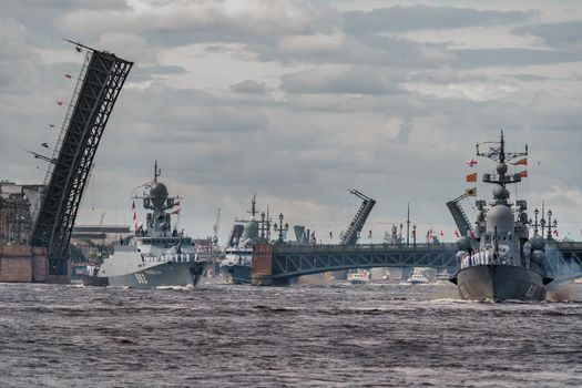 Russia, St. Petersburg, 28 July 2022: A lot of warships goes along the Neva River under open bridges at the time of the rehearsal of the celebration of the day of the Navy in sunny weather. High quality photo