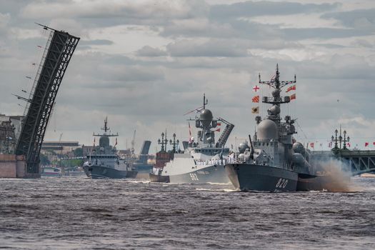 Russia, St. Petersburg, 28 July 2022: A lot of warships goes along the Neva River under open bridges at the time of the rehearsal of the celebration of the day of the Navy in sunny weather. High quality photo