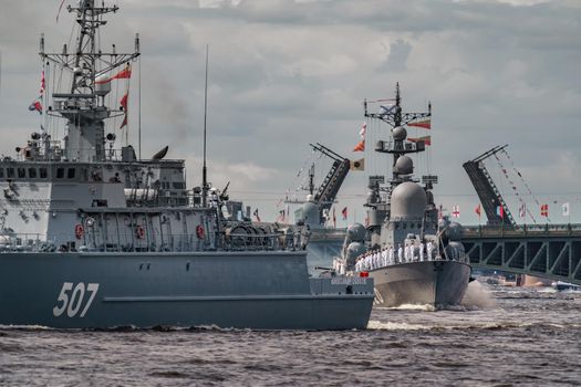 Russia, St. Petersburg, 28 July 2022: A lot of warships goes along the Neva River under open bridges at the time of the rehearsal of the celebration of the day of the Navy in sunny weather. High quality photo
