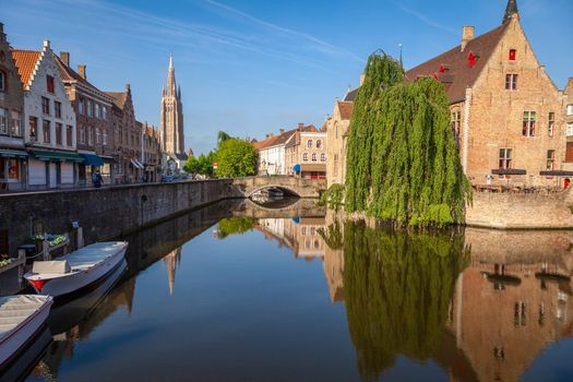 Rozenhoedkaai canal at sunrise with reflection and Church of our Lady, Bruges, Belgium