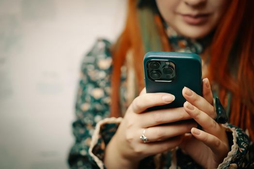 Blogger holds iPhone 13 pro and looks at smartphone screen. Mobile phone in women's hands. Photos for advertising apps and gadgets with copy space. Bishkek, Kyrgyzstan - January 24, 2022